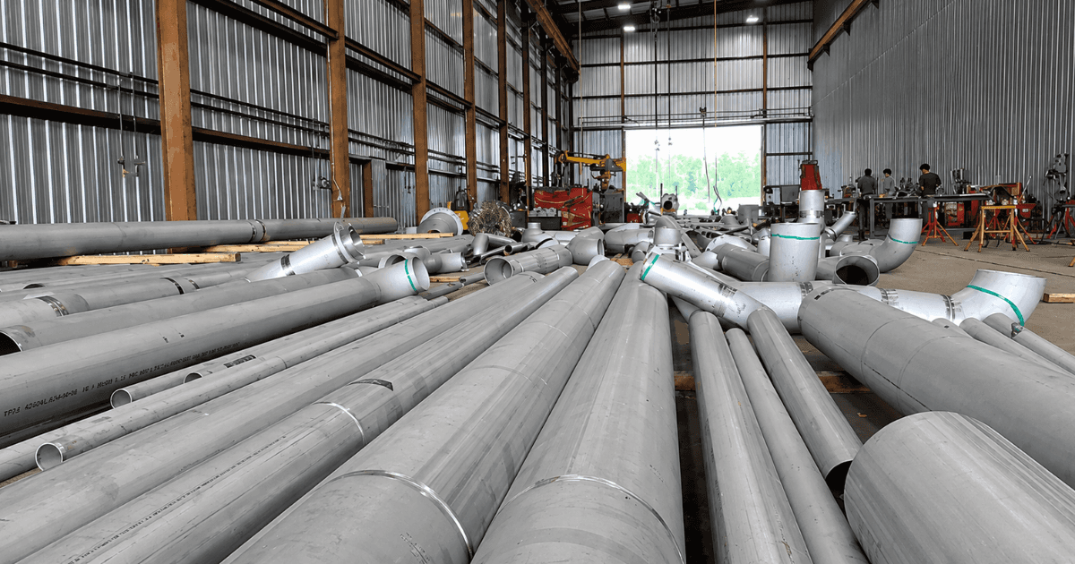Industrial piping fabrication workshop with certified welders fabricating carbon steel pipe spools and process piping systems